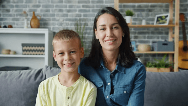 Parent and son sitting on a couch smiling